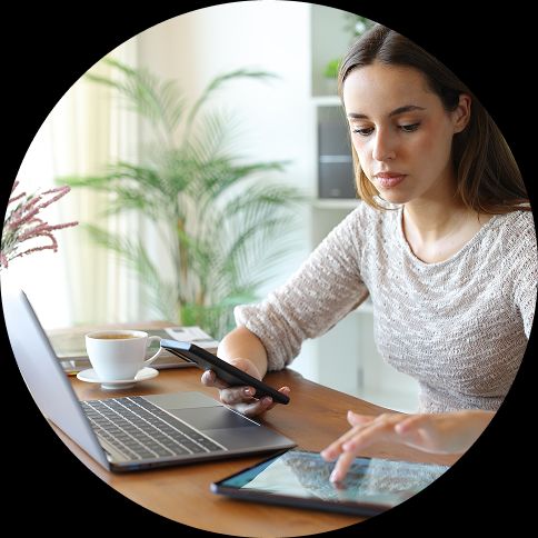 device compatibility testing Image of a woman sitting at a desk with a phone, tablet, and laptop.