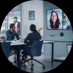 People in a meeting room with other people connected via a screen.