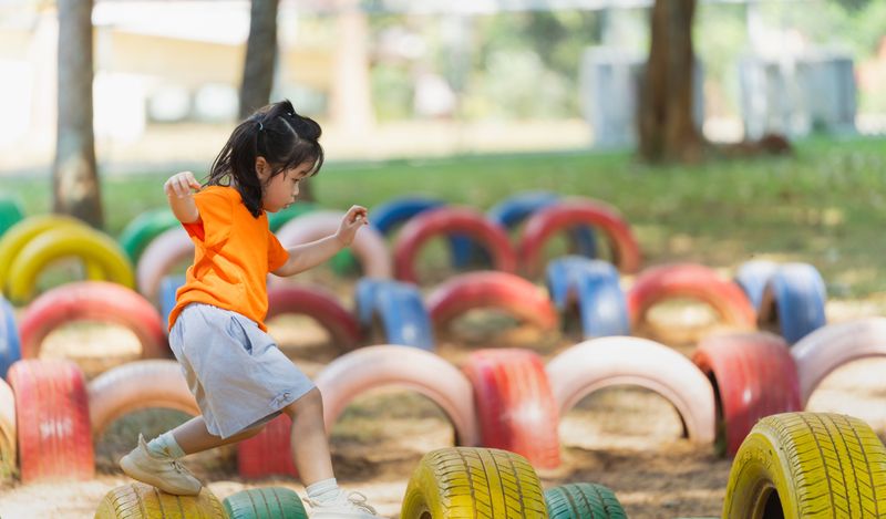 Small child walking across colourful tires