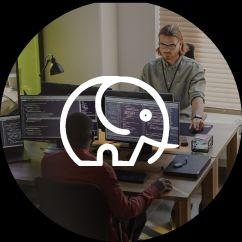 Two men sat desks in an office with large computer screens