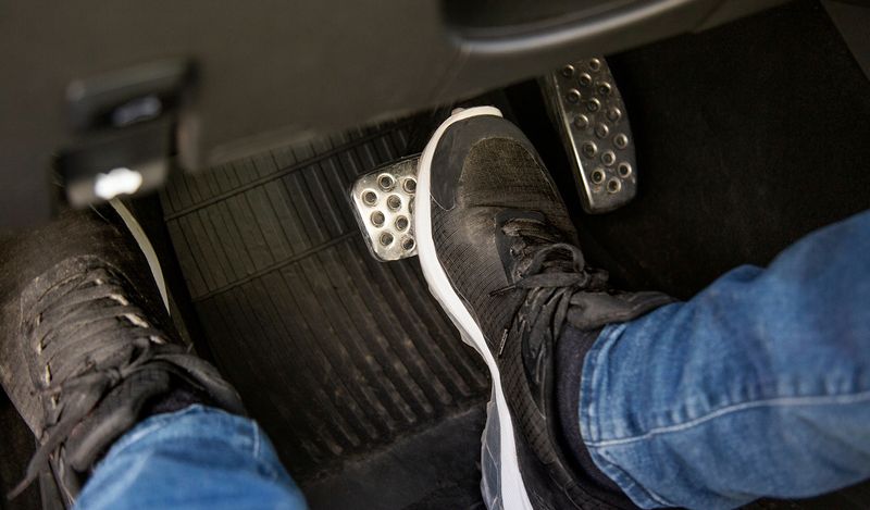 Image of manual car pedals with someone with their feet on the pedals.