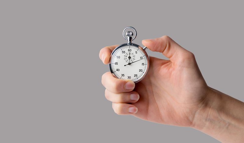 image of a stopwatch in a hand with a gray background