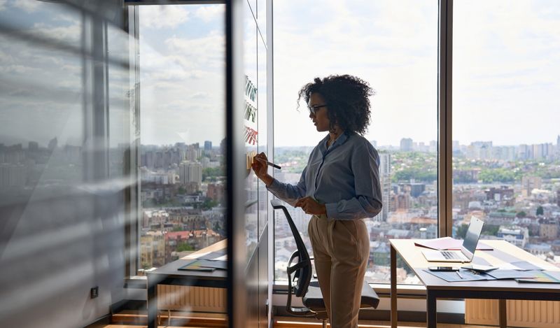 women at a glass screen using post it notes to create a test scenario