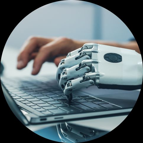 image of human and robotic hands typing at a laptop